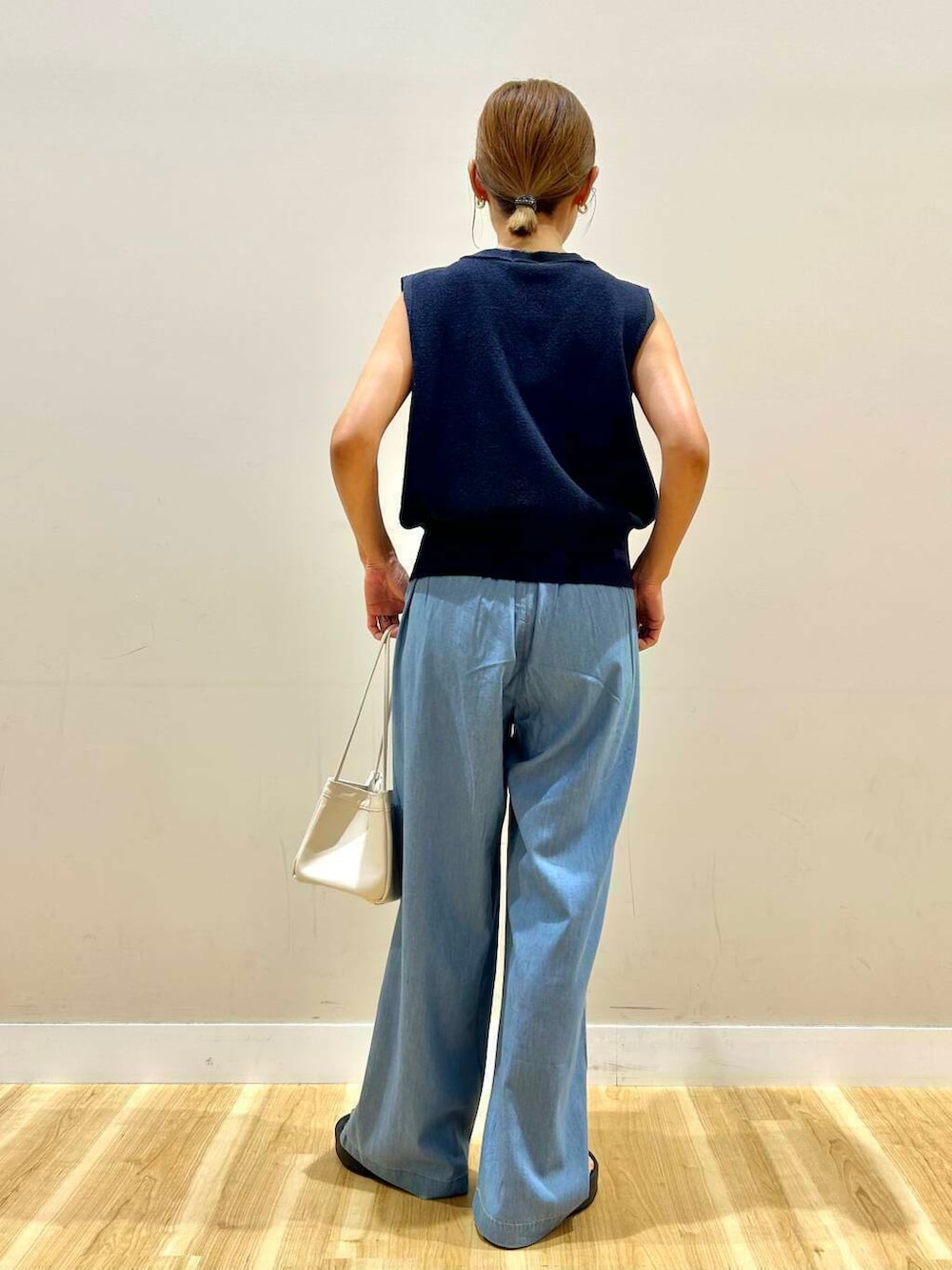ホワイト系のハンドバッグ、ブルー系のデニムパンツ、ブルー系のベストを着用したレディースの夏コーディネートの4枚目の写真