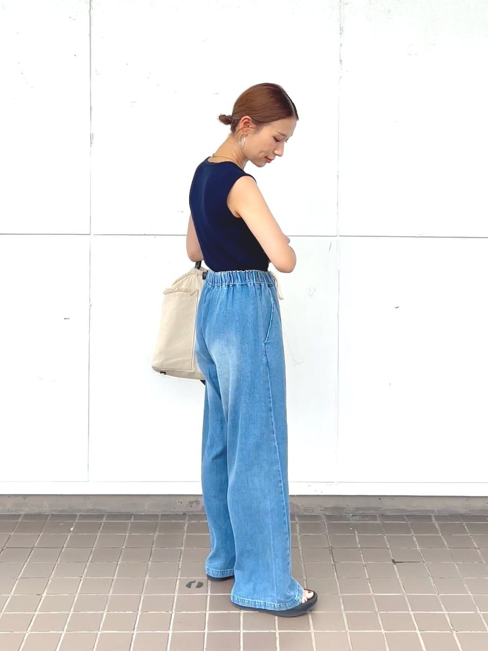 ブルー系のニット/セーター、ブルー系のデニムパンツ、ブラック系のサンダルを着用したレディースの夏コーディネートの2枚目の写真