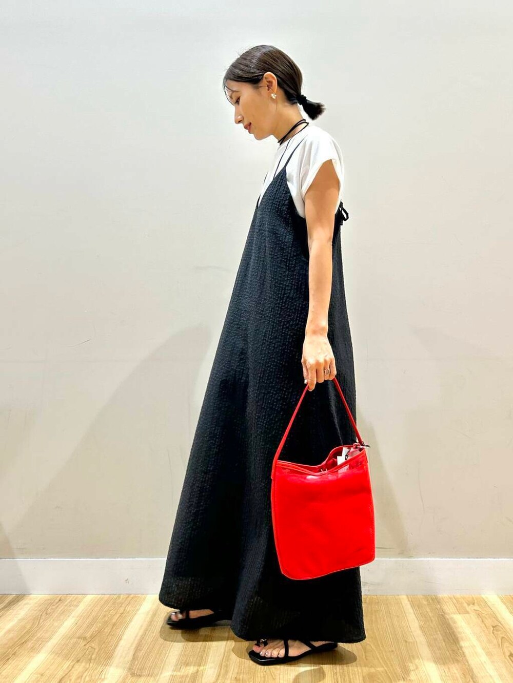 レッド系のショルダーバッグ、ブラック系のサンダル、ブラック系のワンピースを着用したレディースの夏コーディネートの4枚目の写真