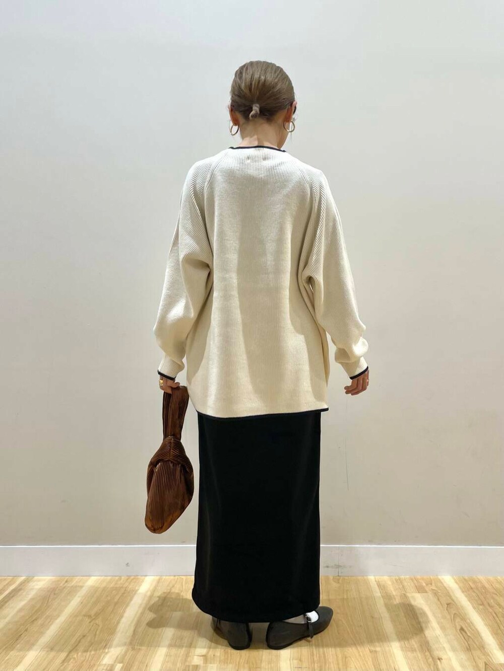 ブラック系のパンプス、ブラウン系のハンドバッグ、ホワイト系のニット/セーターを着用したレディースの冬コーディネートの8枚目の写真