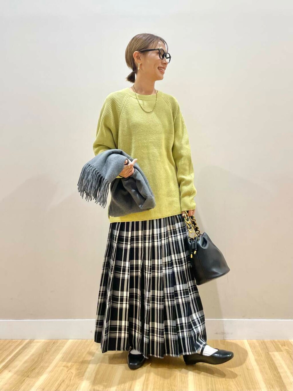 ブラック系のパンプス、ブラック系のショルダーバッグ、イエロー系のニット/セーターを着用したレディースの冬コーディネートの2枚目の写真