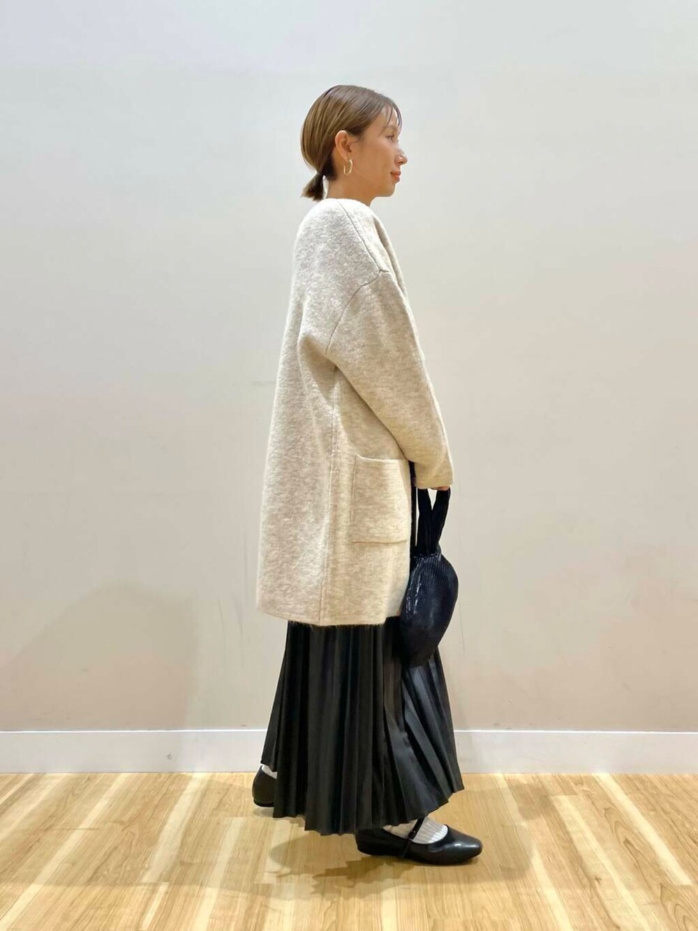 ブラック系のパンプス、ブラック系のハンドバッグ、ベージュ系のカーディガン/ボレロを着用したレディースの冬コーディネートの6枚目の写真