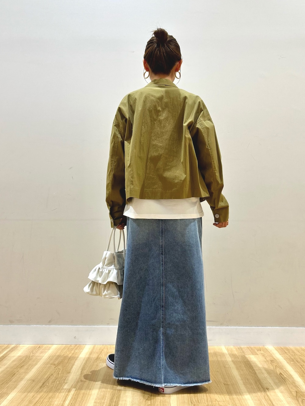 グリーン系のブルゾン、ブラック系のTシャツ/カットソー、ブルー系のスカートを着用したレディースの春コーディネートの2枚目の写真