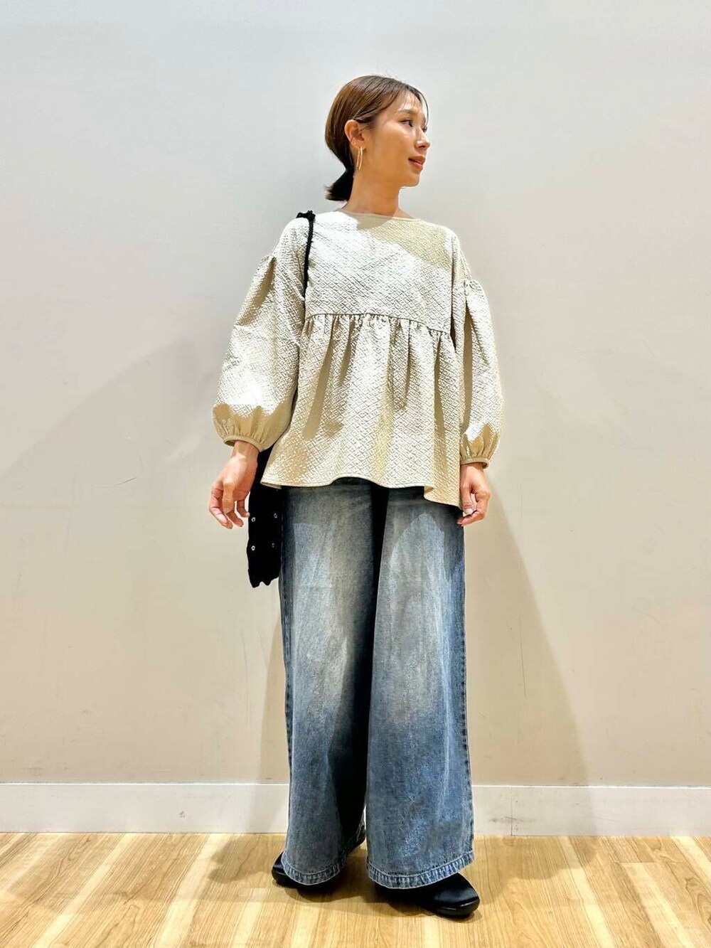 ブラック系のショルダーバッグ、ブルー系のデニムパンツ、ベージュ系のシャツ/ブラウスを着用したレディースの春コーディネートの2枚目の写真