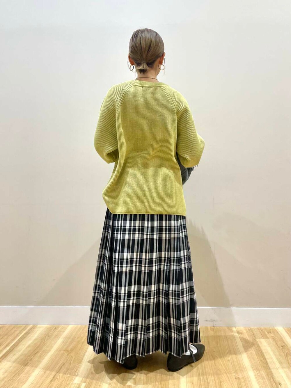 ブラック系のパンプス、ブラック系のショルダーバッグ、イエロー系のニット/セーターを着用したレディースの冬コーディネートの5枚目の写真