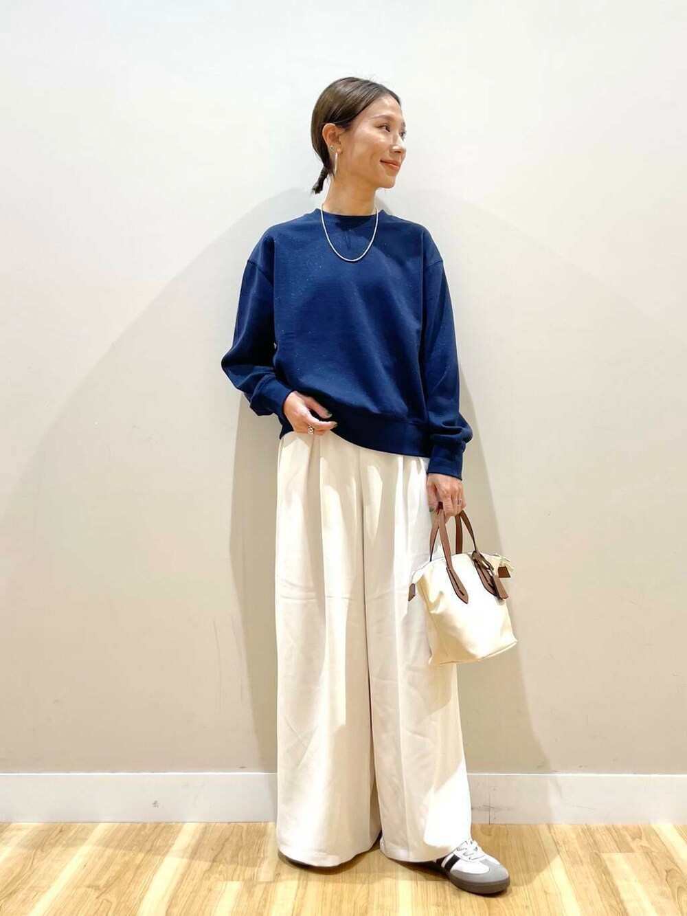 ホワイト系のトートバッグ、ブルー系のスウェット、ホワイト系のスニーカーを着用したレディースの秋コーディネートの2枚目の写真