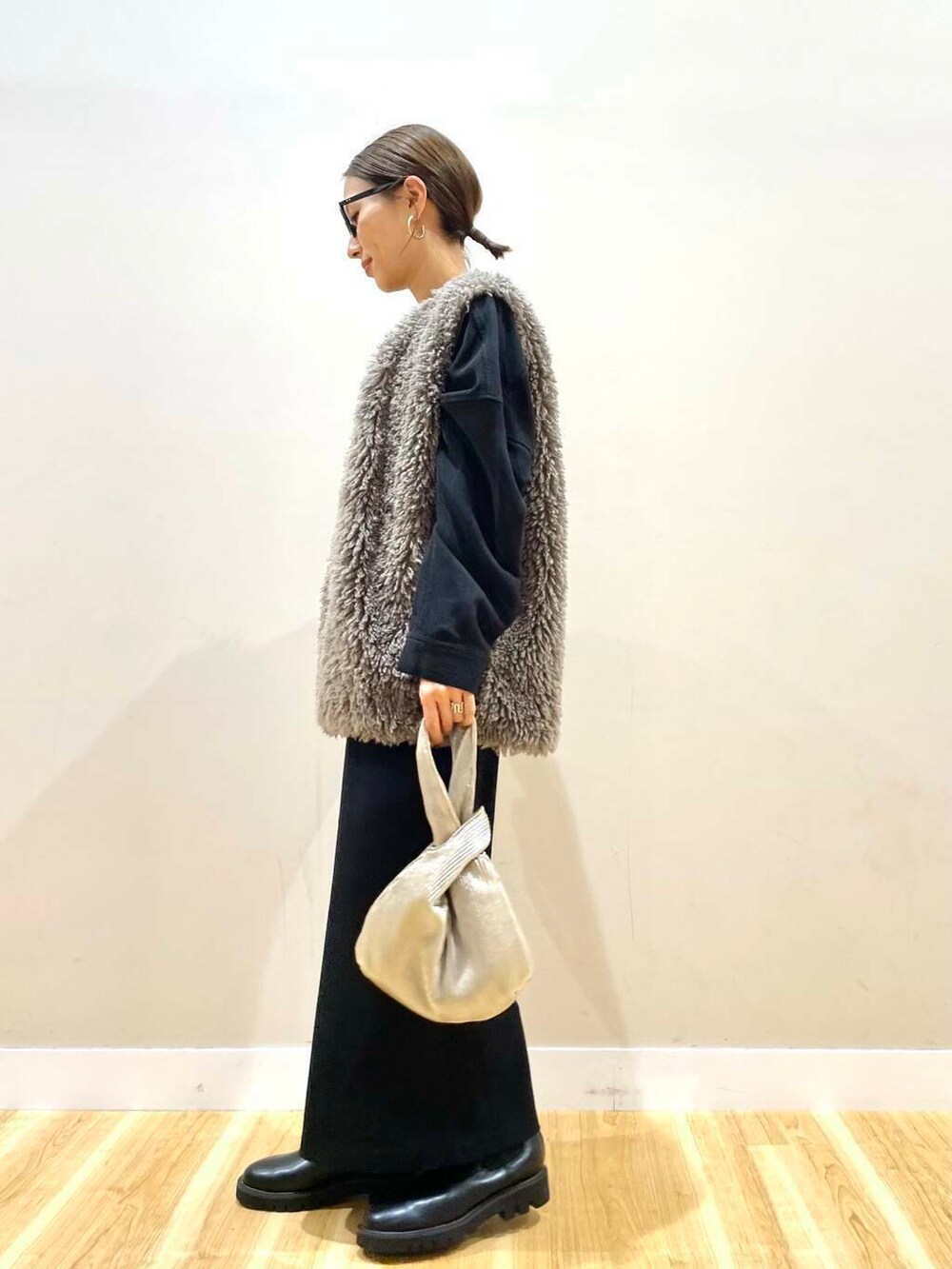 ブラック系のブーツ、グレー系のベスト、ゴールド系のハンドバッグを着用したレディースの秋コーディネートの5枚目の写真