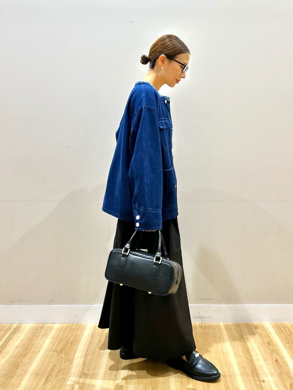 ブルー系のデニムジャケット、グレー系のニット/セーター、ブラック系のスカートを着用したレディースの秋コーディネートの2枚目の写真