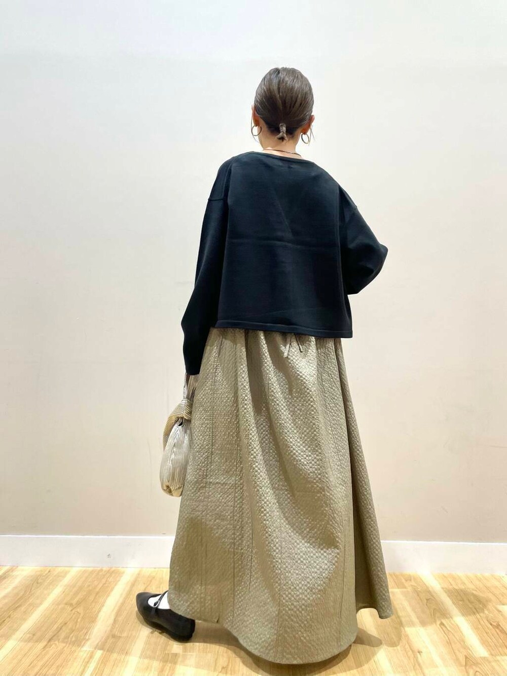 ブラック系のパンプス、ゴールド系のハンドバッグ、ブラック系のタンクトップを着用したレディースの秋コーディネートの4枚目の写真