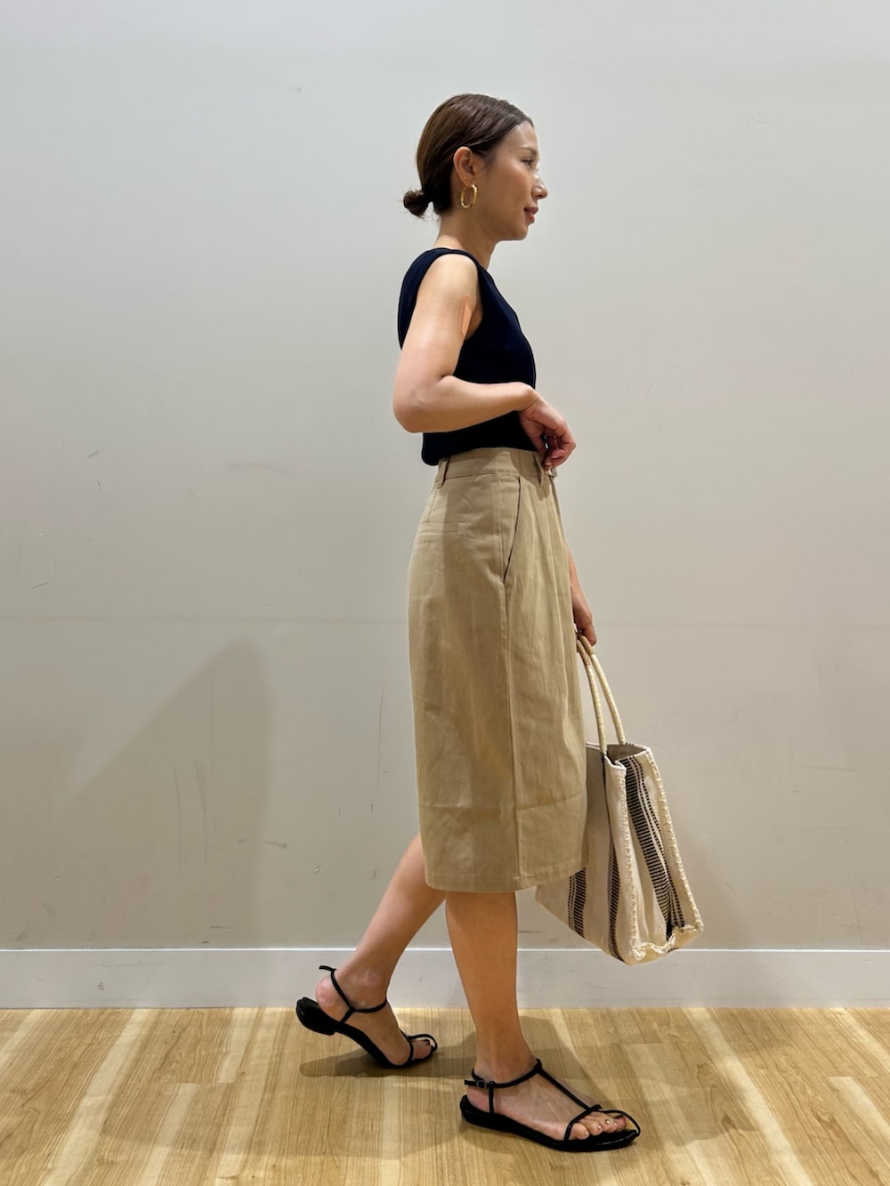 ブルー系のニット/セーター、ベージュ系のその他パンツ、ホワイト系のトートバッグを着用したレディースの夏コーディネートの3枚目の写真
