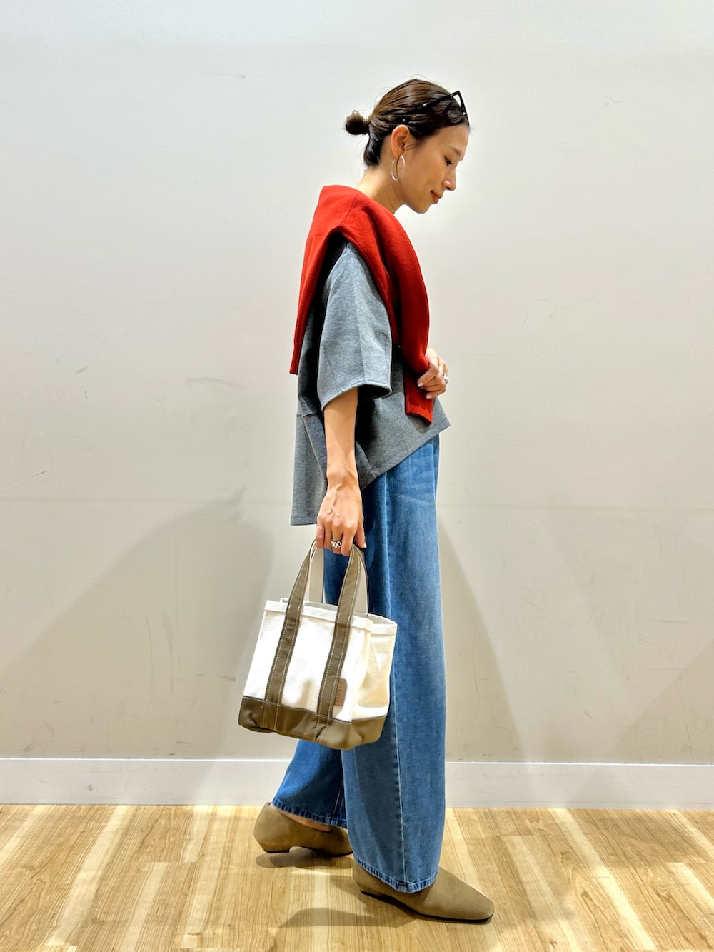 レッド系のニット/セーター、グレー系のTシャツ/カットソー、グレー系のトートバッグを着用したレディースの秋コーディネートの2枚目の写真