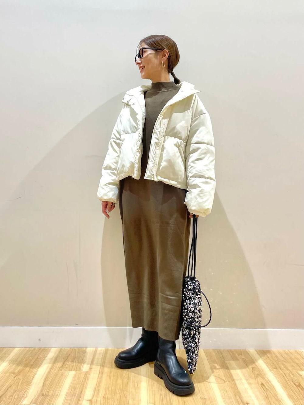 ブラウン系のワンピース、シルバー系のトートバッグ、ホワイト系のダウンジャケット/コートを着用したレディースの冬コーディネートの3枚目の写真