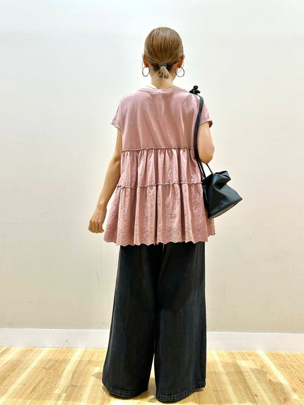 ブラック系のデニムパンツ、ブラック系のショルダーバッグ、ピンク系のTシャツ/カットソーを着用したレディースの夏コーディネートの3枚目の写真