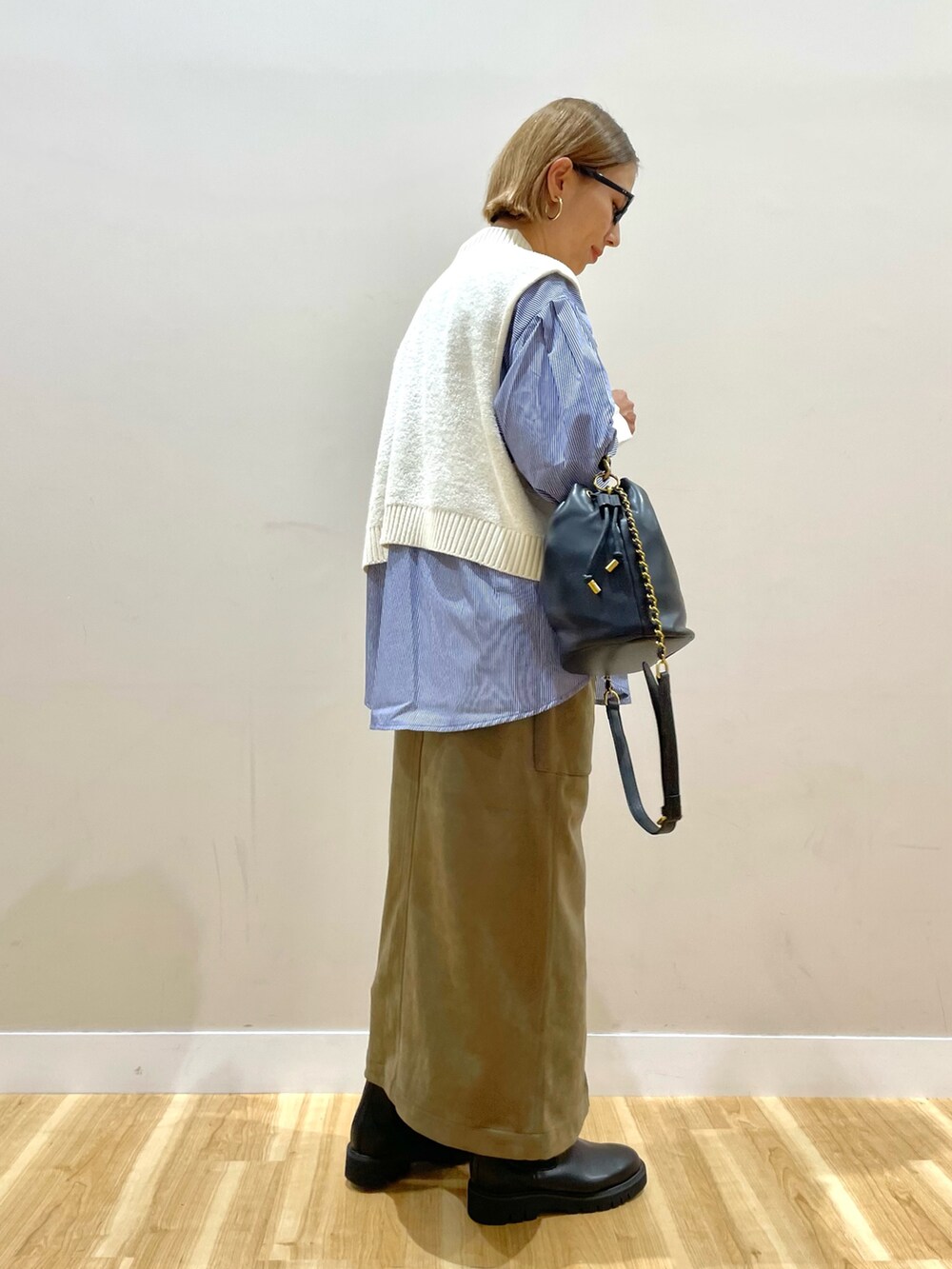 ホワイト系のニット/セーター、ブルー系のシャツ/ブラウス、グリーン系のスカートを着用したレディースの秋コーディネートの2枚目の写真