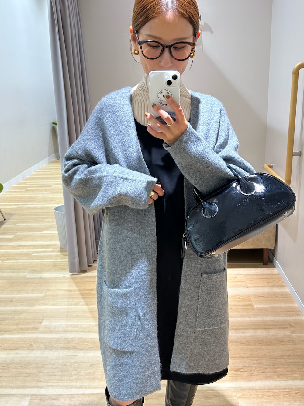 グレー系のノーカラーコート、ブラック系のワンピース、ホワイト系のニット/セーターを着用したレディースの秋コーディネートの3枚目の写真