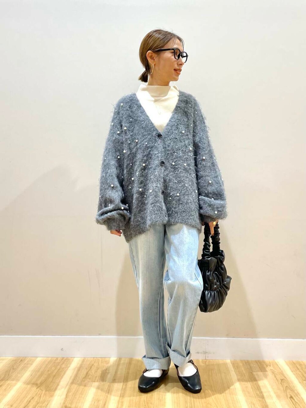 ブラック系のパンプス、ブラック系のハンドバッグ、ブルー系のデニムパンツを着用したレディースの秋コーディネートの2枚目の写真