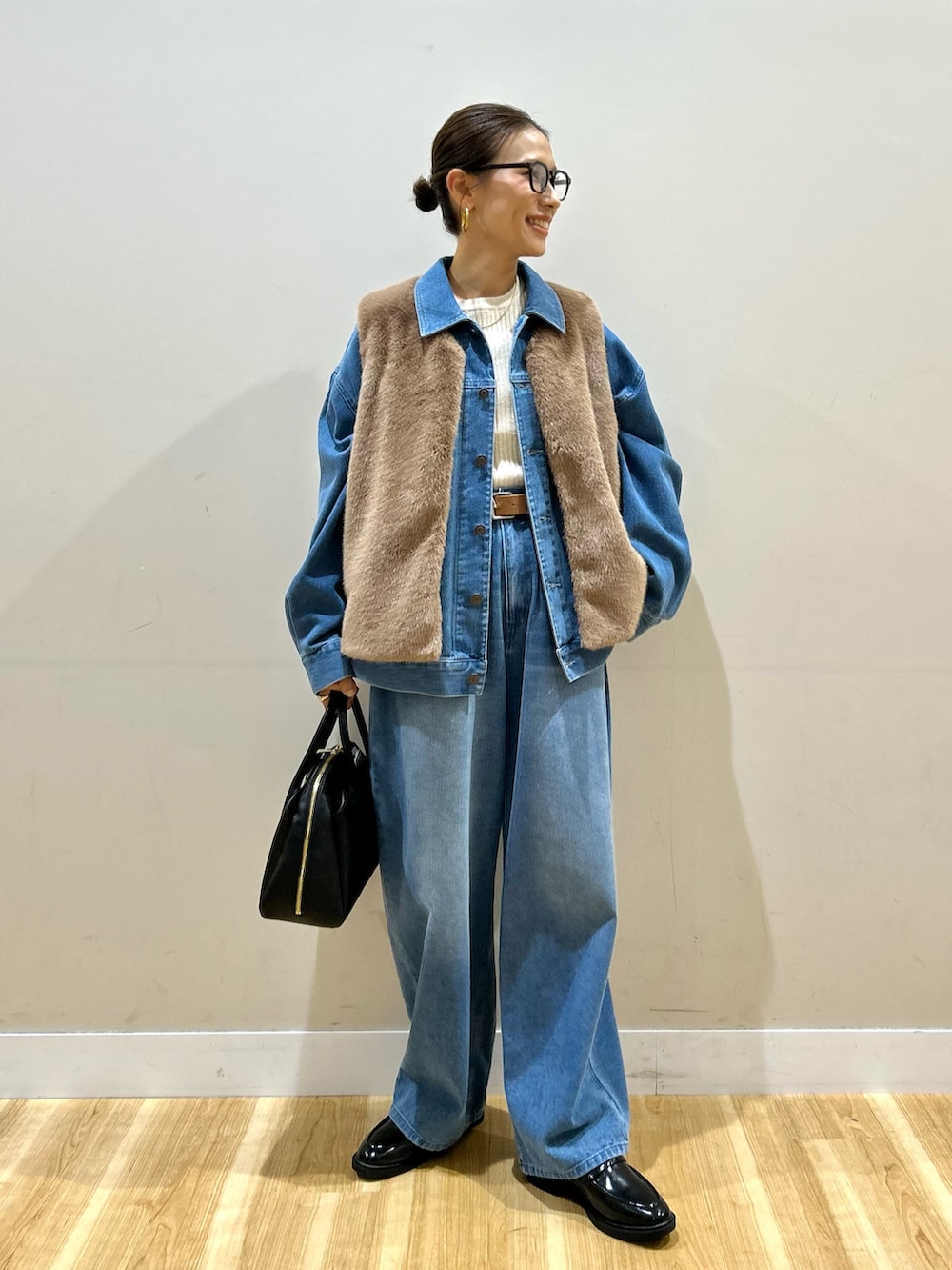ブルー系のカバーオール、ブルー系のその他パンツ、ブラウン系のダウンベストを着用したレディースの秋コーディネートの5枚目の写真