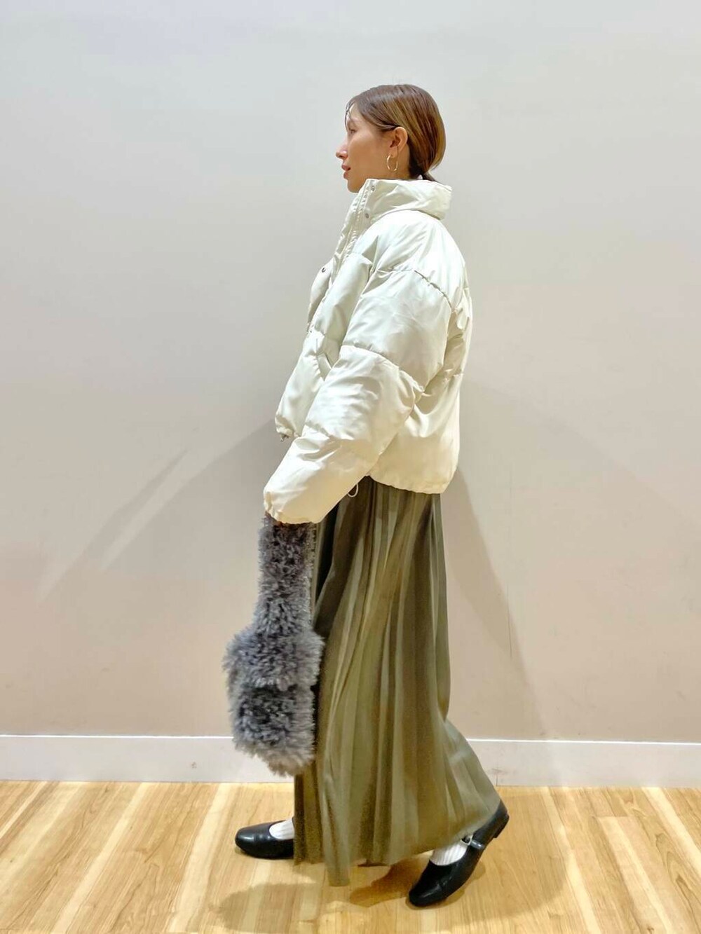 ブラック系のパンプス、グリーン系のスカート、グレー系のハンドバッグを着用したレディースの冬コーディネートの4枚目の写真