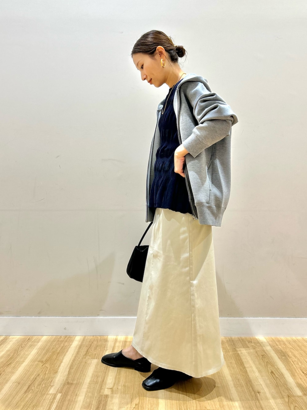 グレー系のパーカー、ブルー系のニット/セーター、ブラック系のスリッポンを着用したレディースの春コーディネートの2枚目の写真