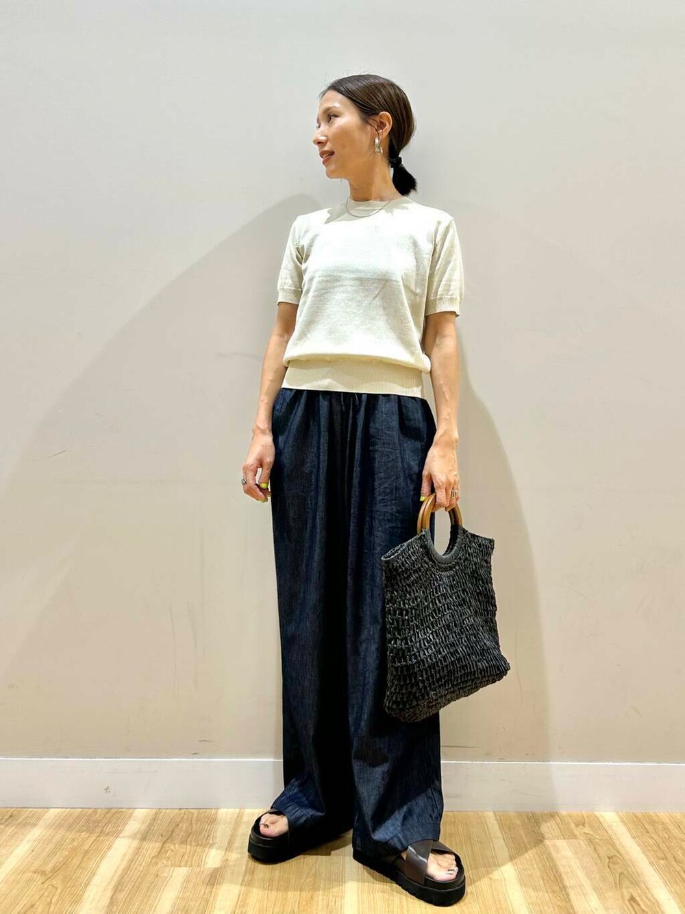 ブラック系のトートバッグ、ブラウン系のサンダル、ホワイト系のニット/セーターを着用したレディースの夏コーディネートの5枚目の写真