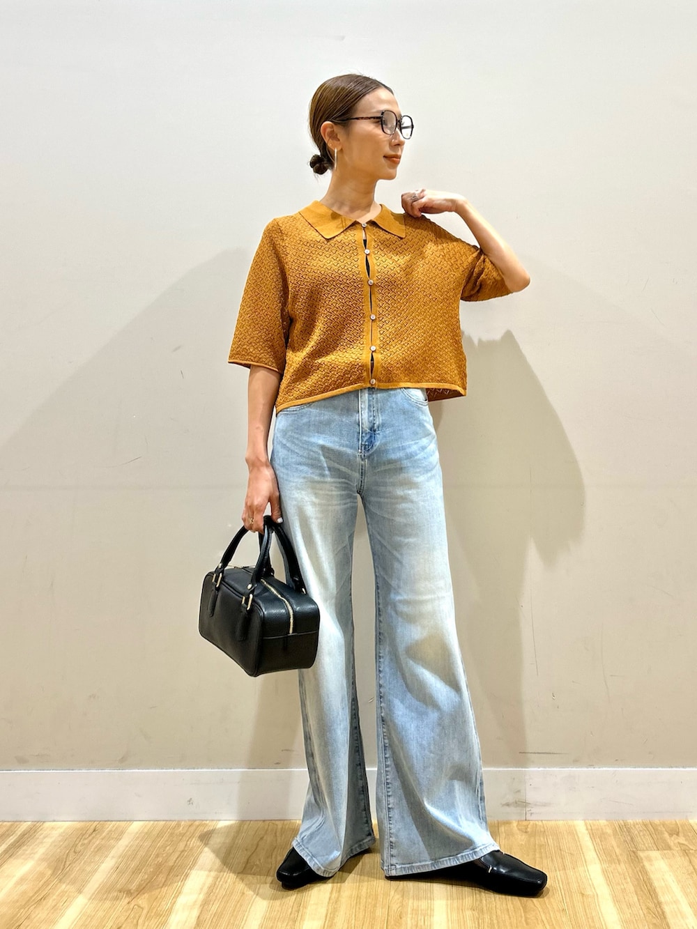 ブラウン系のニット/セーター、ブルー系のデニムパンツ、ブラック系のハンドバッグを着用したレディースの夏コーディネートの2枚目の写真