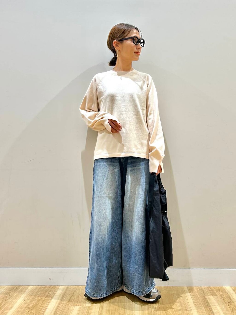 ホワイト系のニット/セーター、ブルー系のデニムパンツ、ブラック系のトートバッグを着用したレディースの春コーディネートの6枚目の写真
