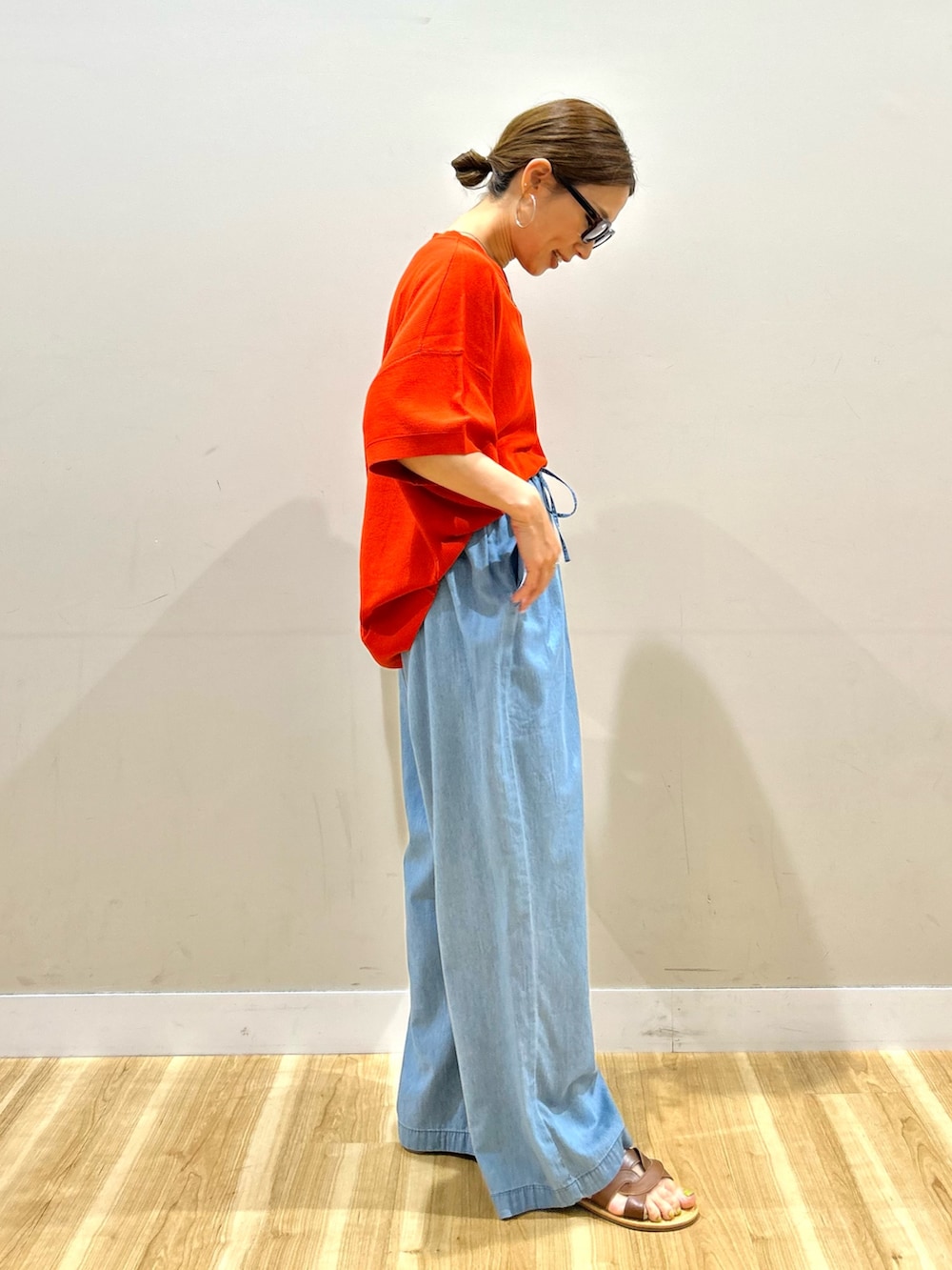 ブルー系のデニムパンツ、グレー系のハンドバッグ、ブラウン系のサンダルを着用したレディースの夏コーディネートの2枚目の写真