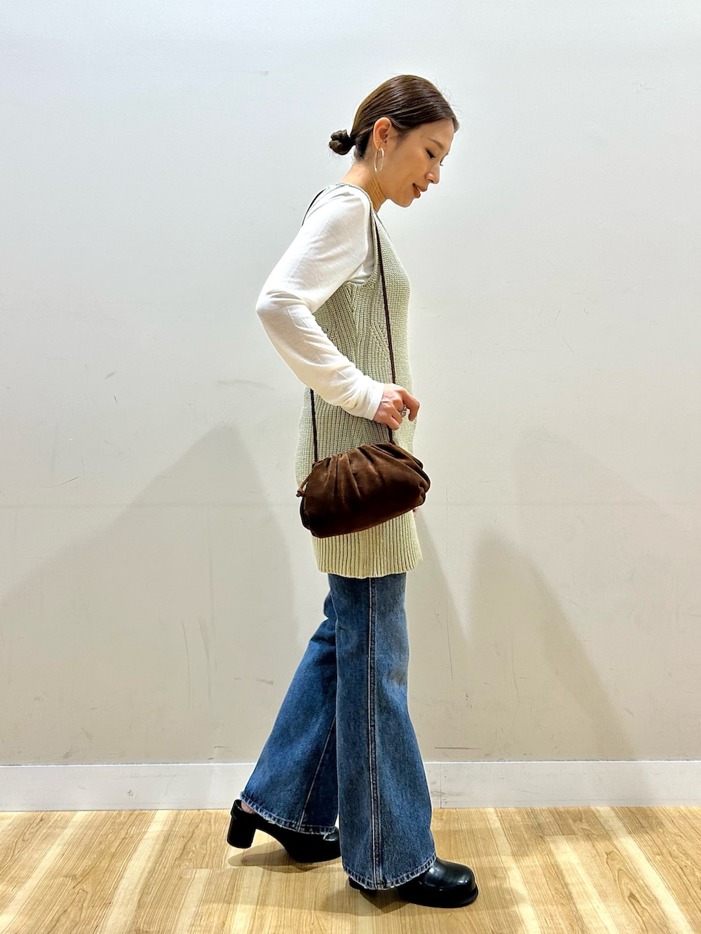 ベージュ系のベスト、ブルー系のデニムパンツ、ブラック系のその他シューズを着用したレディースの春コーディネートの2枚目の写真