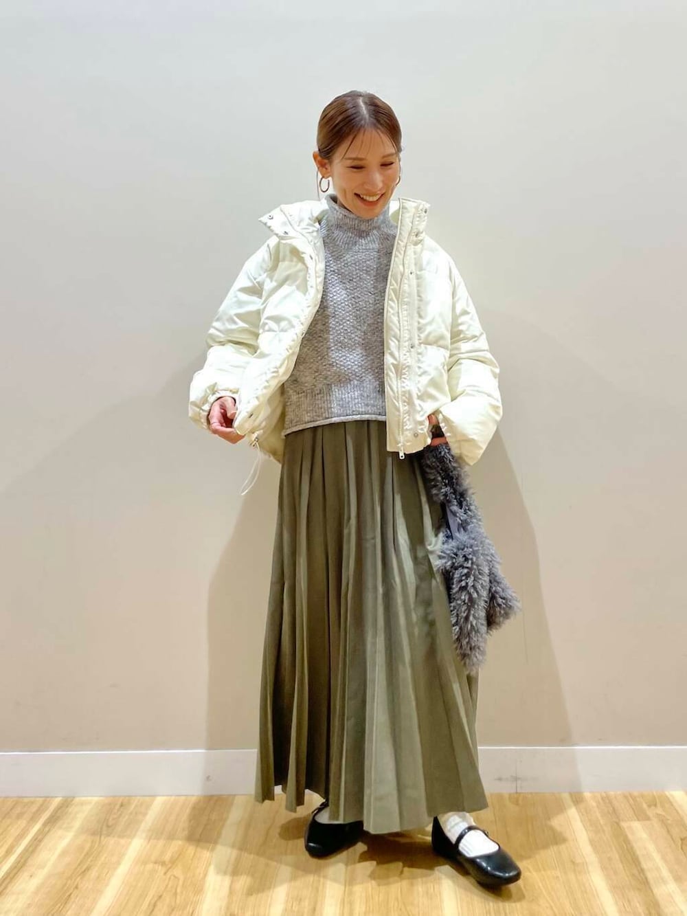 ブラック系のパンプス、グリーン系のスカート、グレー系のハンドバッグを着用したレディースの冬コーディネートの3枚目の写真