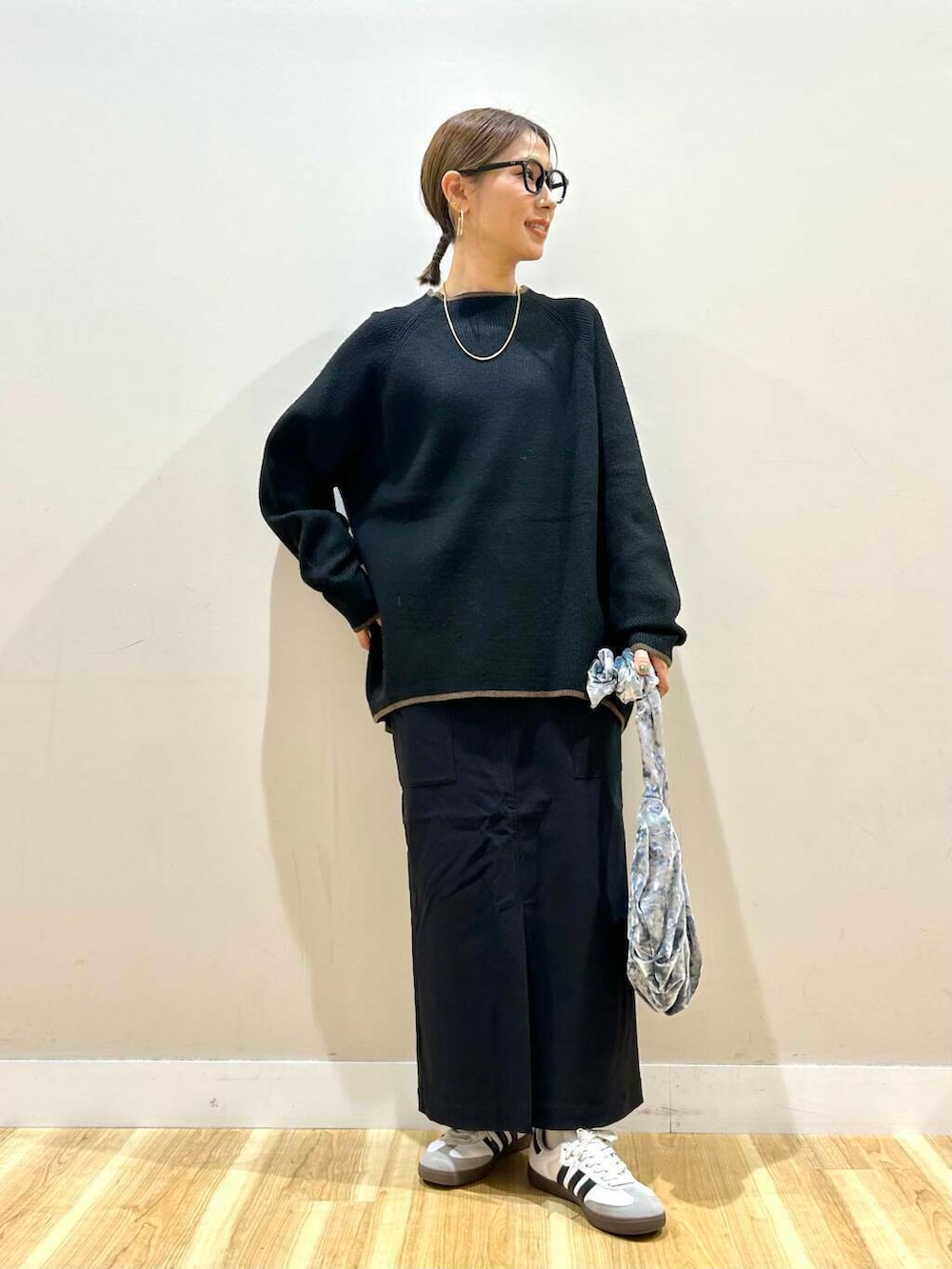 グレー系のハンドバッグ、ブラック系のニット/セーター、ブラック系のスカートを着用したレディースの冬コーディネートの2枚目の写真