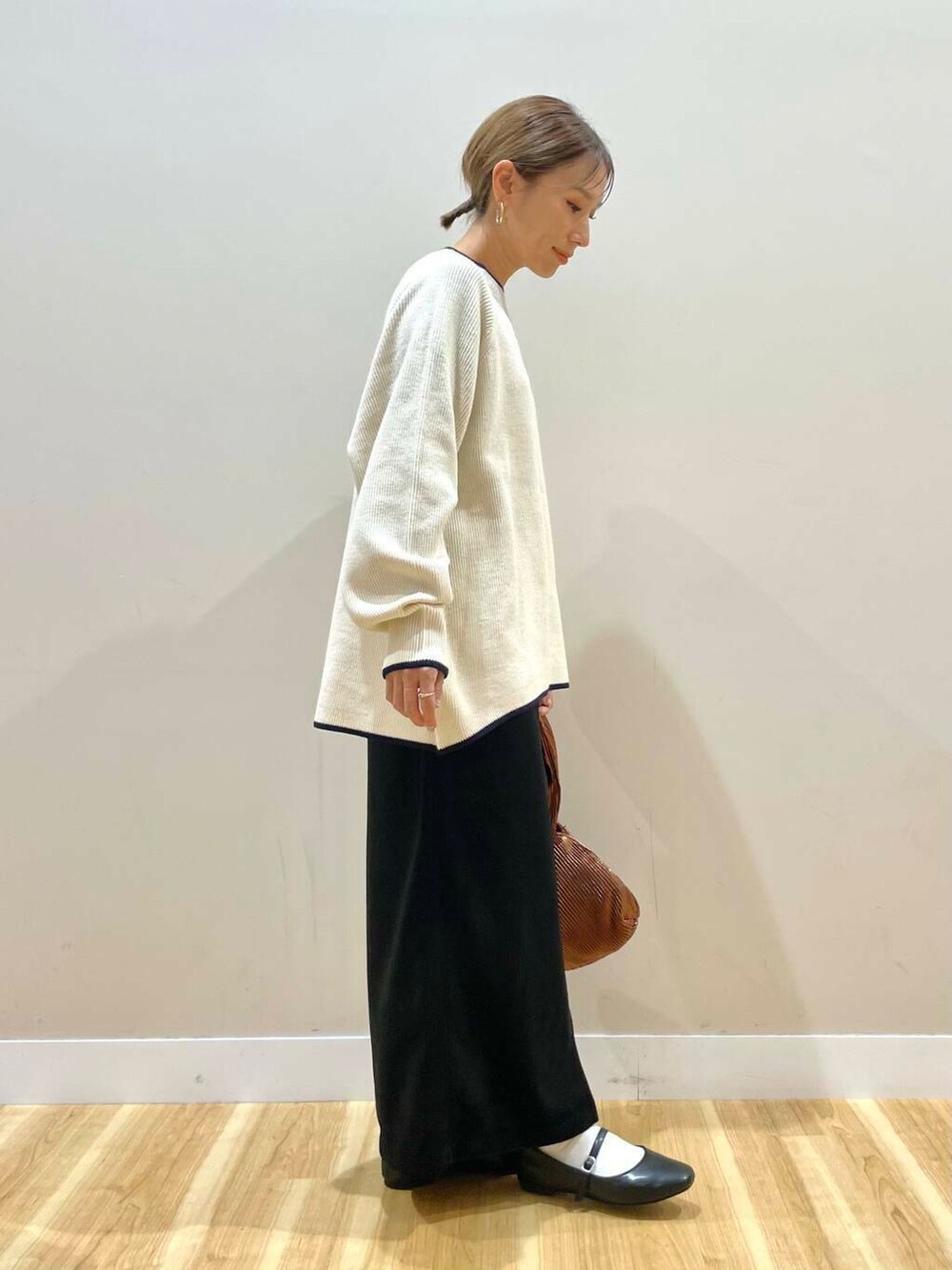 ブラック系のパンプス、ブラウン系のハンドバッグ、ホワイト系のニット/セーターを着用したレディースの冬コーディネートの7枚目の写真