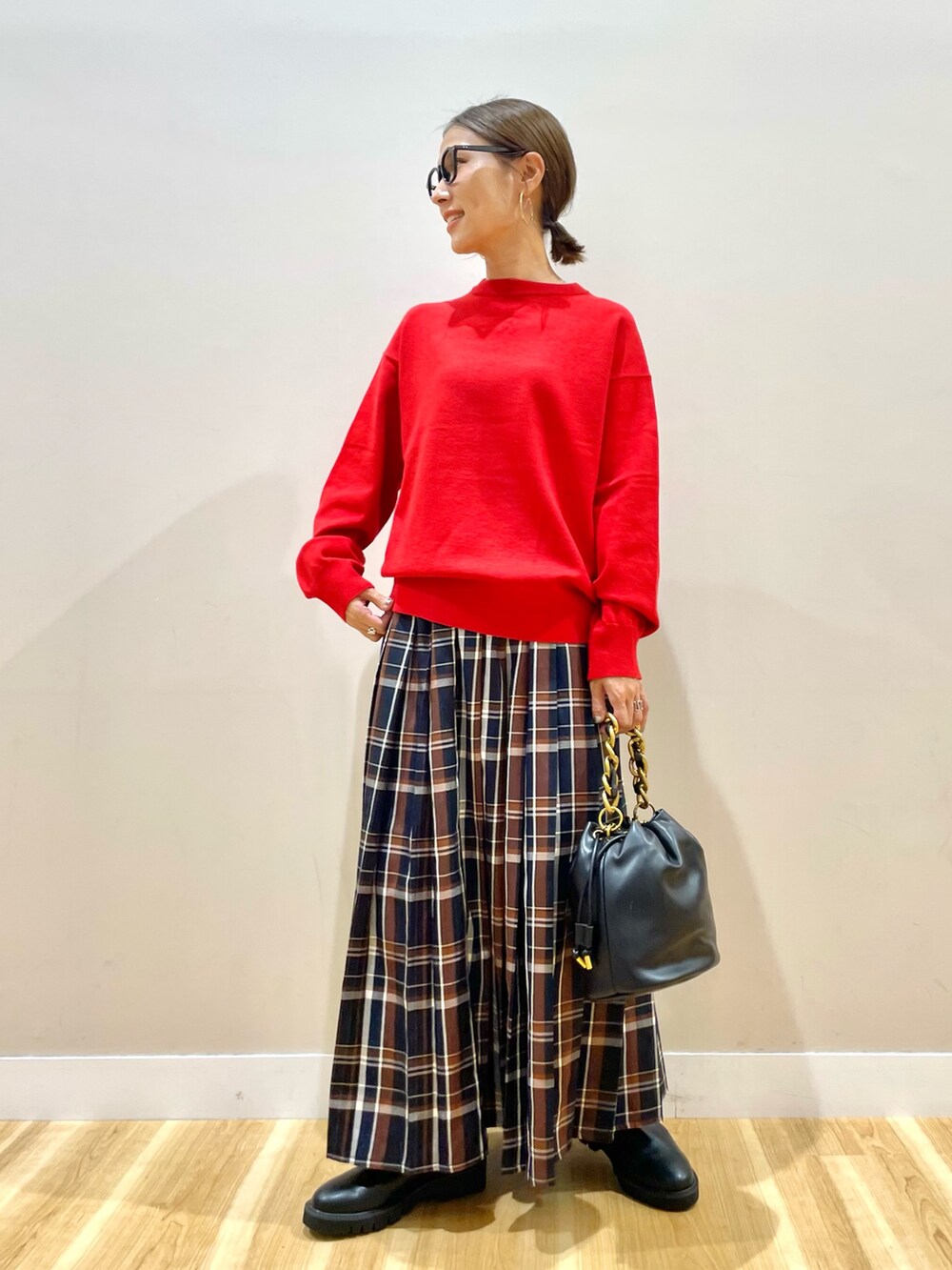レッド系のニット/セーター、ブルー系のスカートを着用したレディースの秋コーディネートの6枚目の写真