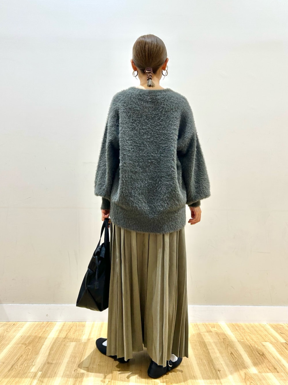 グレー系のニット/セーター、グリーン系のスカート、ブラック系のショルダーバッグを着用したレディースの秋コーディネートの3枚目の写真