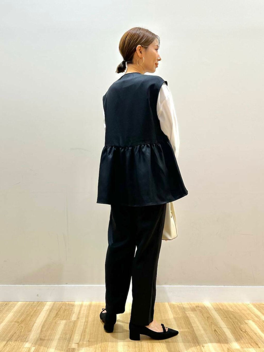 ホワイト系のトートバッグ、ブラック系のパンプス、ブラック系のセットアップを着用したレディースの冬コーディネートの3枚目の写真