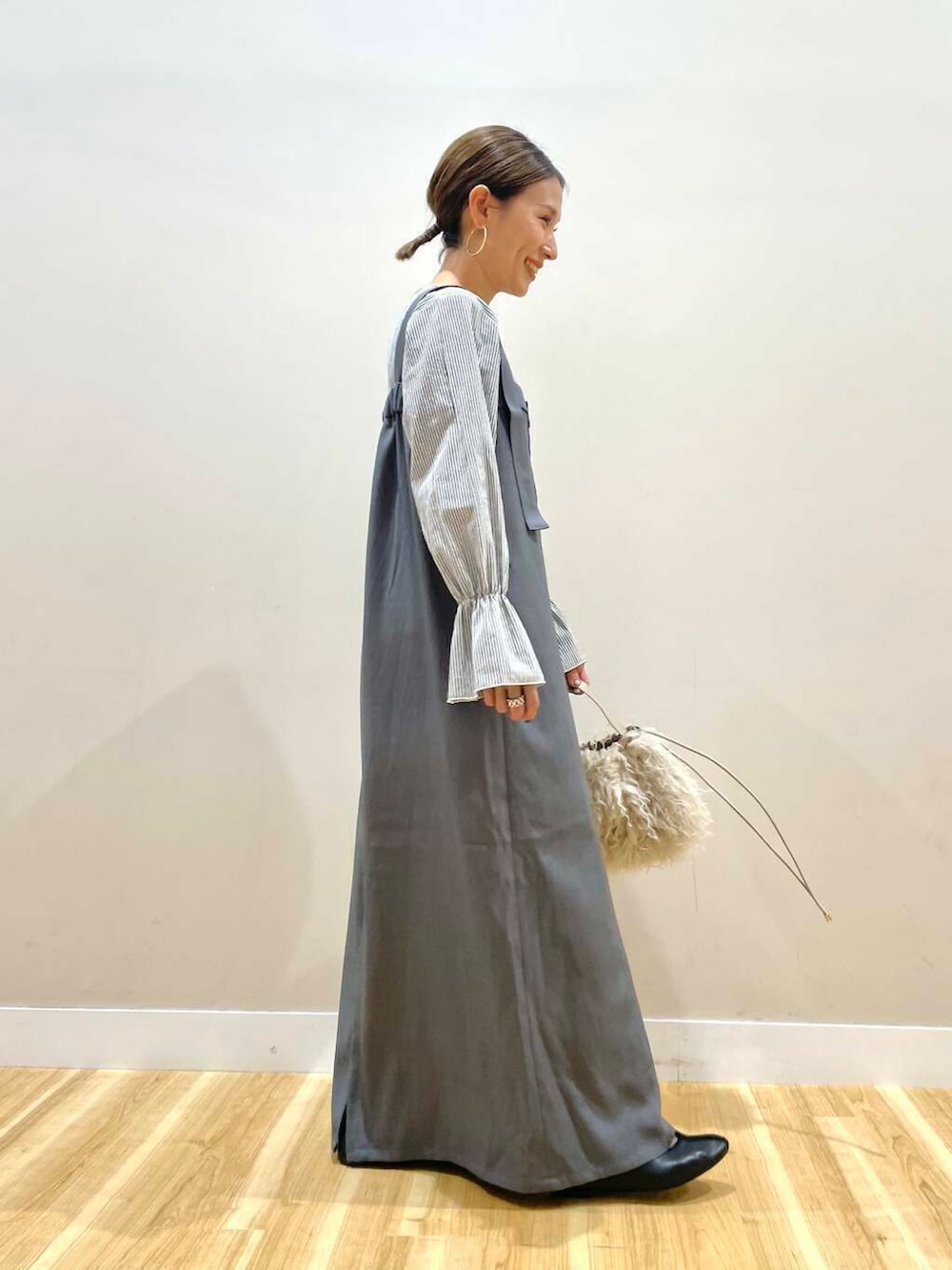 ベージュ系のショルダーバッグ、グレー系のジャンパースカートを着用したレディースの秋コーディネートの2枚目の写真