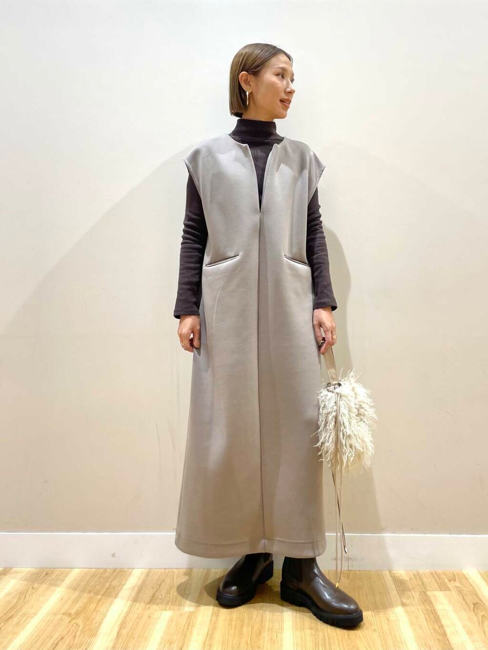 ブラウン系のブーツ、ベージュ系のショルダーバッグ、ブラウン系のジャンパースカートを着用したレディースの秋コーディネートの4枚目の写真