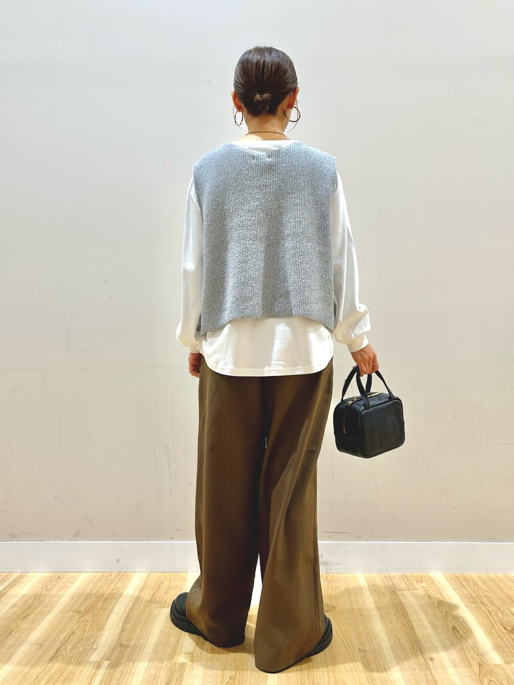 グレー系のベスト、ブラウン系のその他パンツ、ブラック系のボストンバッグを着用したレディースの冬コーディネートの3枚目の写真