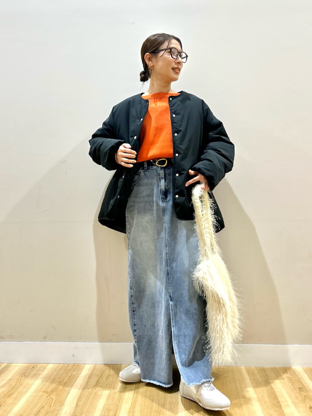 ブラック系のダウンジャケット/コート、オレンジ系のニット/セーター、ブルー系のスカートを着用したレディースの冬コーディネートの8枚目の写真