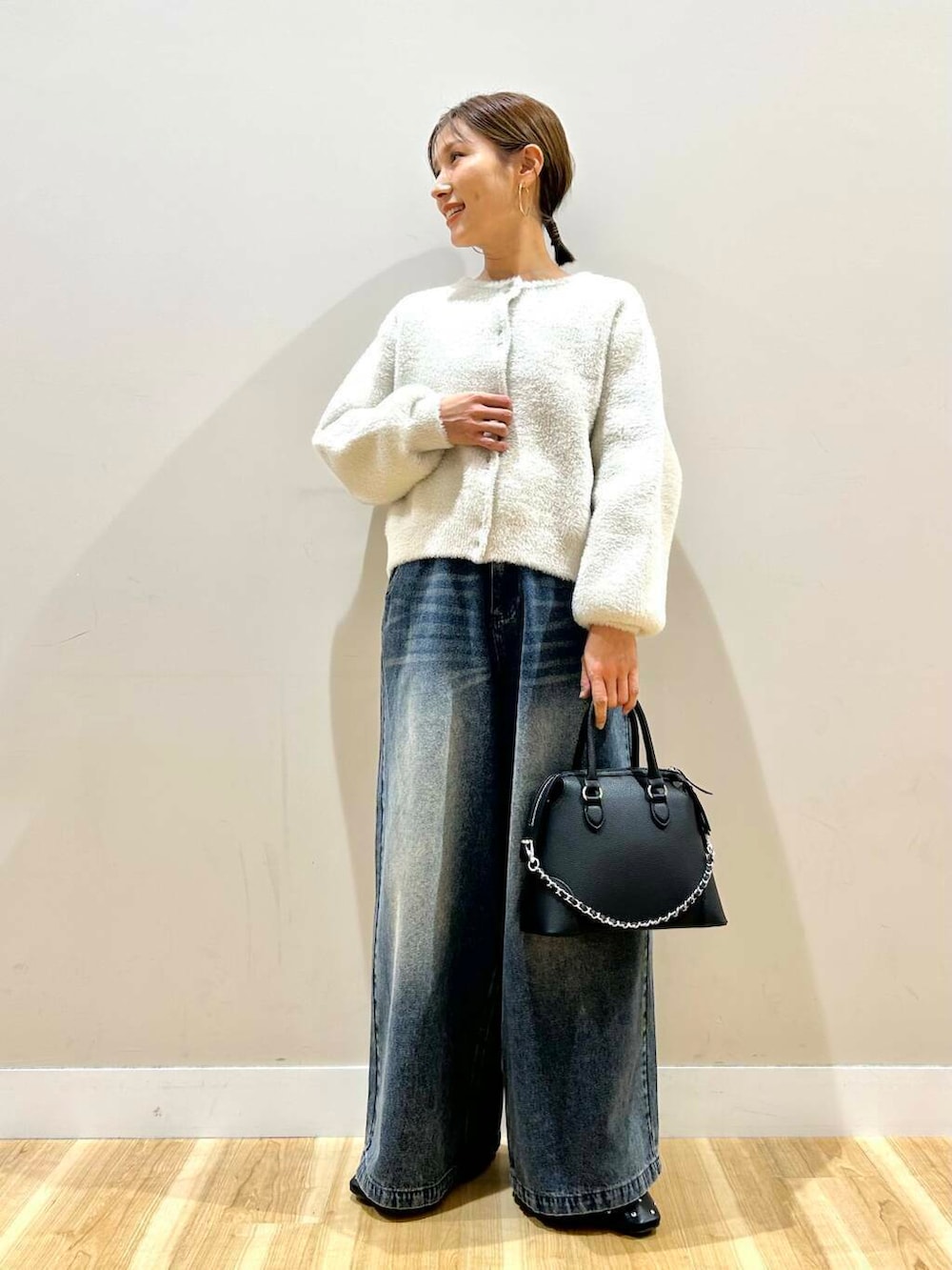 ブラック系のボストンバッグ、ブラック系のパンプス、ホワイト系のカーディガン/ボレロを着用したレディースの冬コーディネートの4枚目の写真