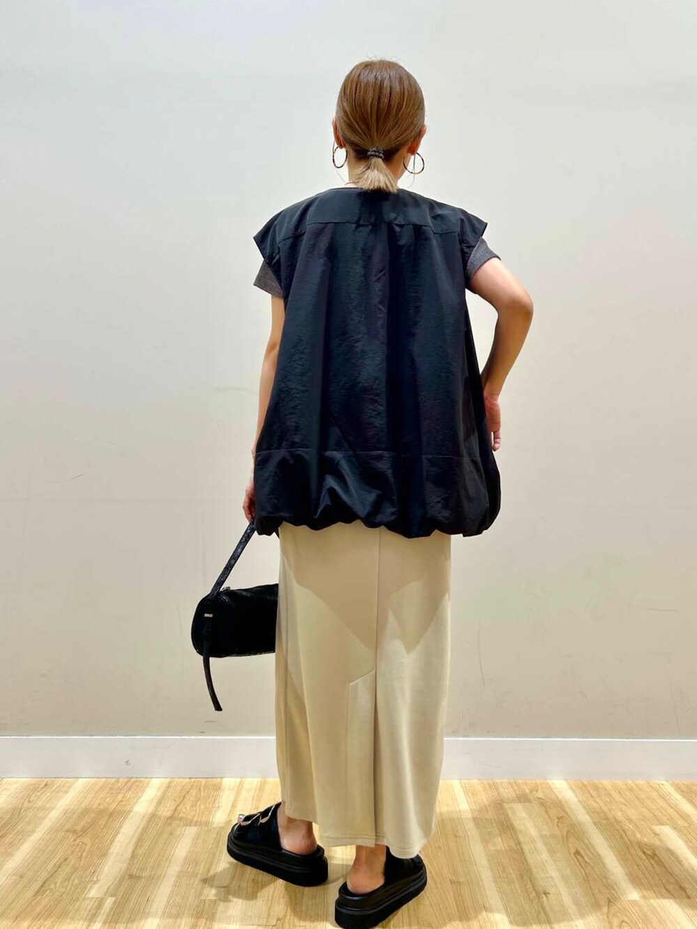 ブラック系のハンドバッグ、グレー系のTシャツ/カットソー、グリーン系のスカートを着用したレディースの夏コーディネートの3枚目の写真