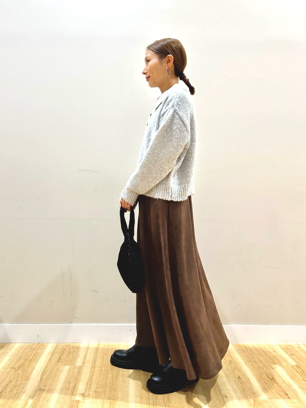 ブラック系のダウンジャケット/コート、グレー系のニット/セーター、ブラウン系のスカートを着用したレディースの秋コーディネートの5枚目の写真