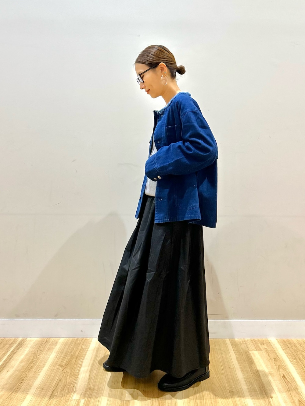 ブルー系のデニムジャケット、グレー系のニット/セーター、ブラック系のスカートを着用したレディースの秋コーディネートの4枚目の写真