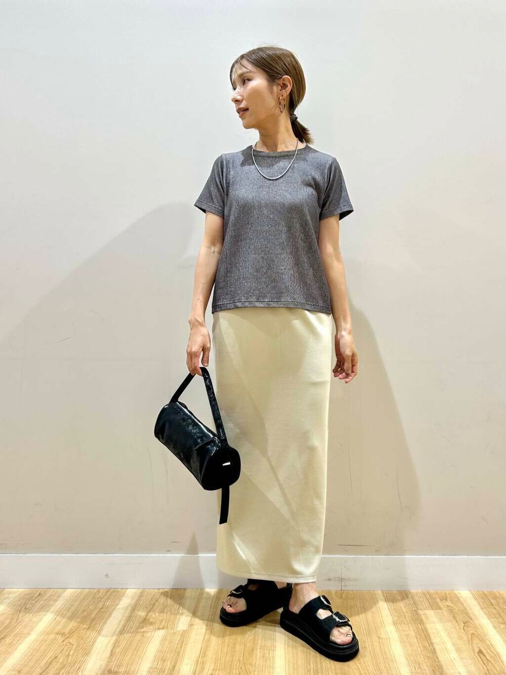 ブラック系のハンドバッグ、グレー系のTシャツ/カットソー、グリーン系のスカートを着用したレディースの夏コーディネートの6枚目の写真