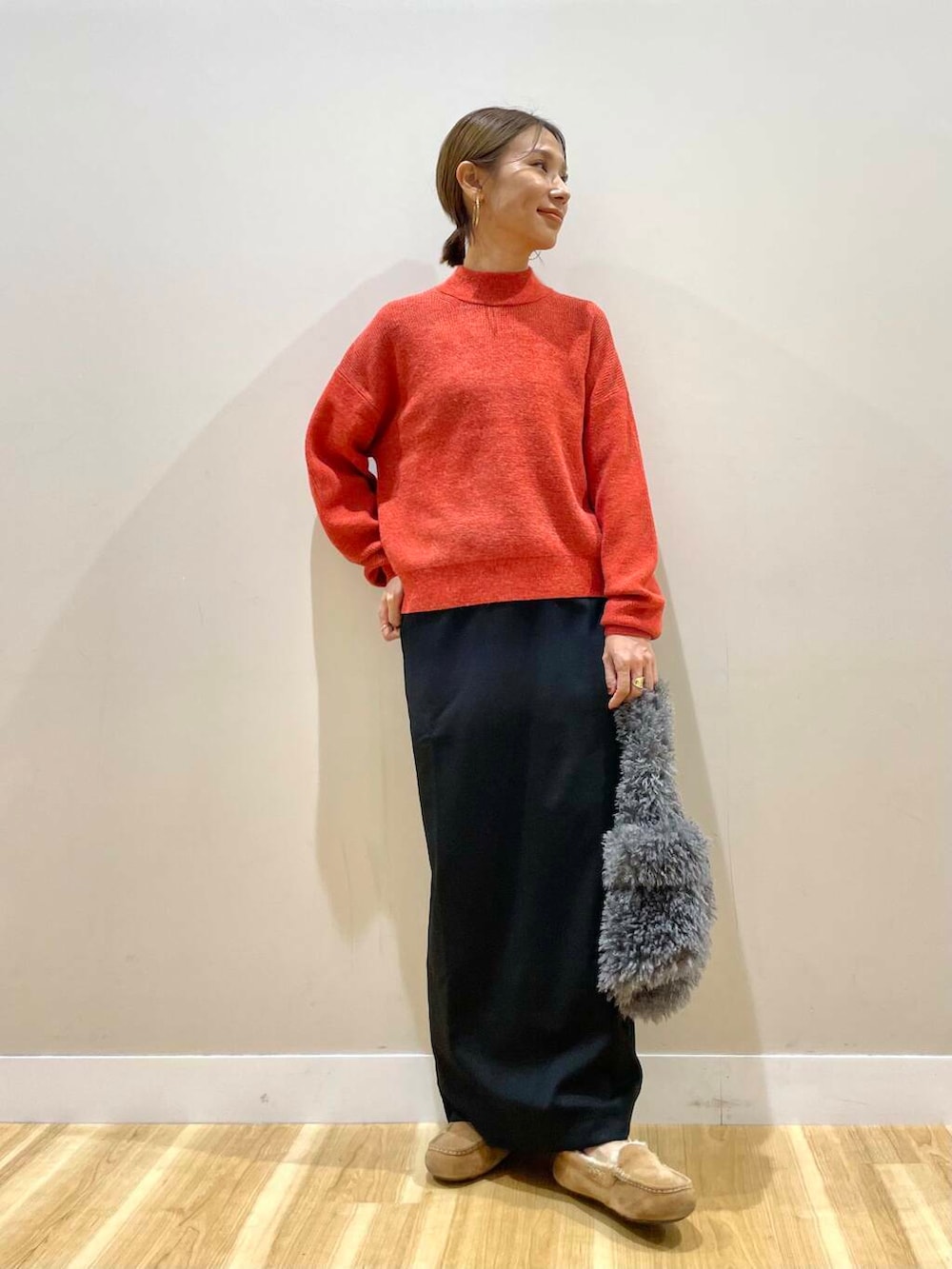 ブラック系のスカート、グレー系のハンドバッグ、レッド系のニット/セーターを着用したレディースの秋コーディネートの2枚目の写真