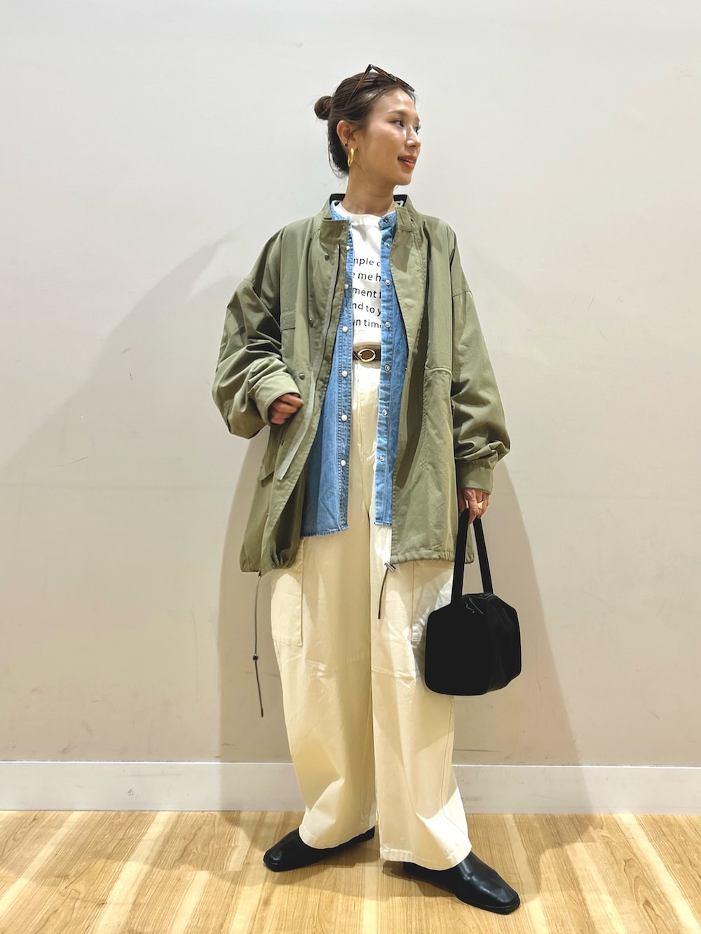 グリーン系のモッズコート、ブルー系のシャツ/ブラウス、ベージュ系のTシャツ/カットソーを着用したレディースの春コーディネートの2枚目の写真