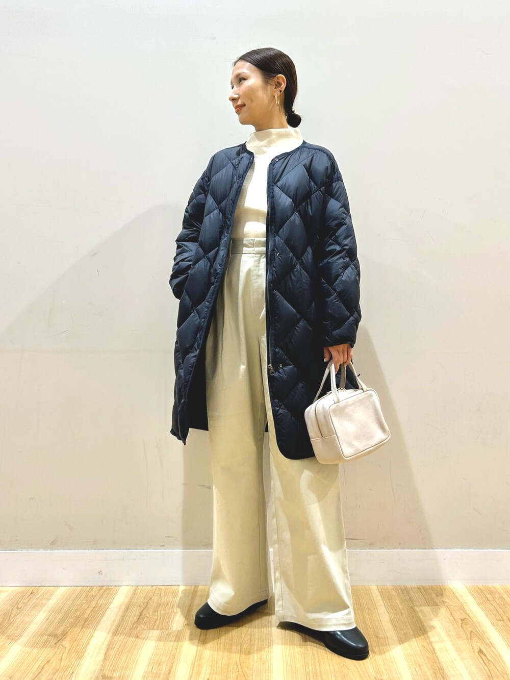 ブルー系のダウンジャケット/コート、ホワイト系のニット/セーター、ベージュ系のその他パンツを着用したレディースの冬コーディネートの7枚目の写真