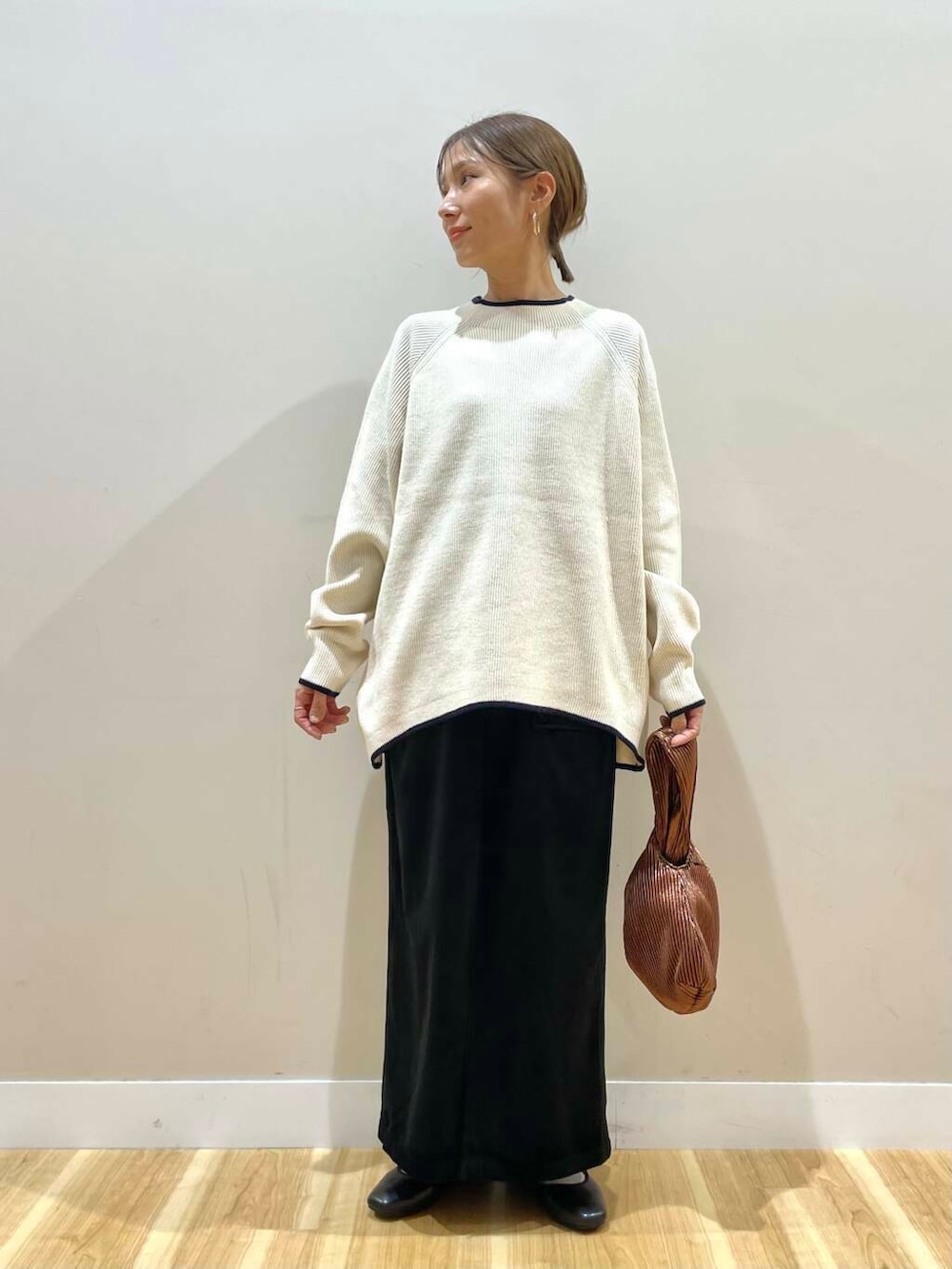 ブラック系のパンプス、ブラウン系のハンドバッグ、ホワイト系のニット/セーターを着用したレディースの冬コーディネートの9枚目の写真