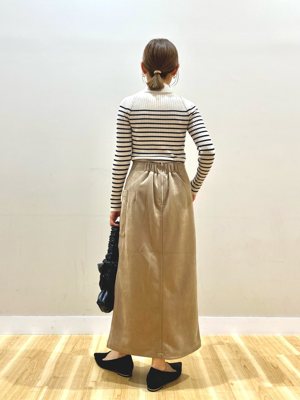 ブラック系のベスト、ホワイト系のニット/セーター、ブラウン系のスカートを着用したレディースの秋コーディネートの5枚目の写真