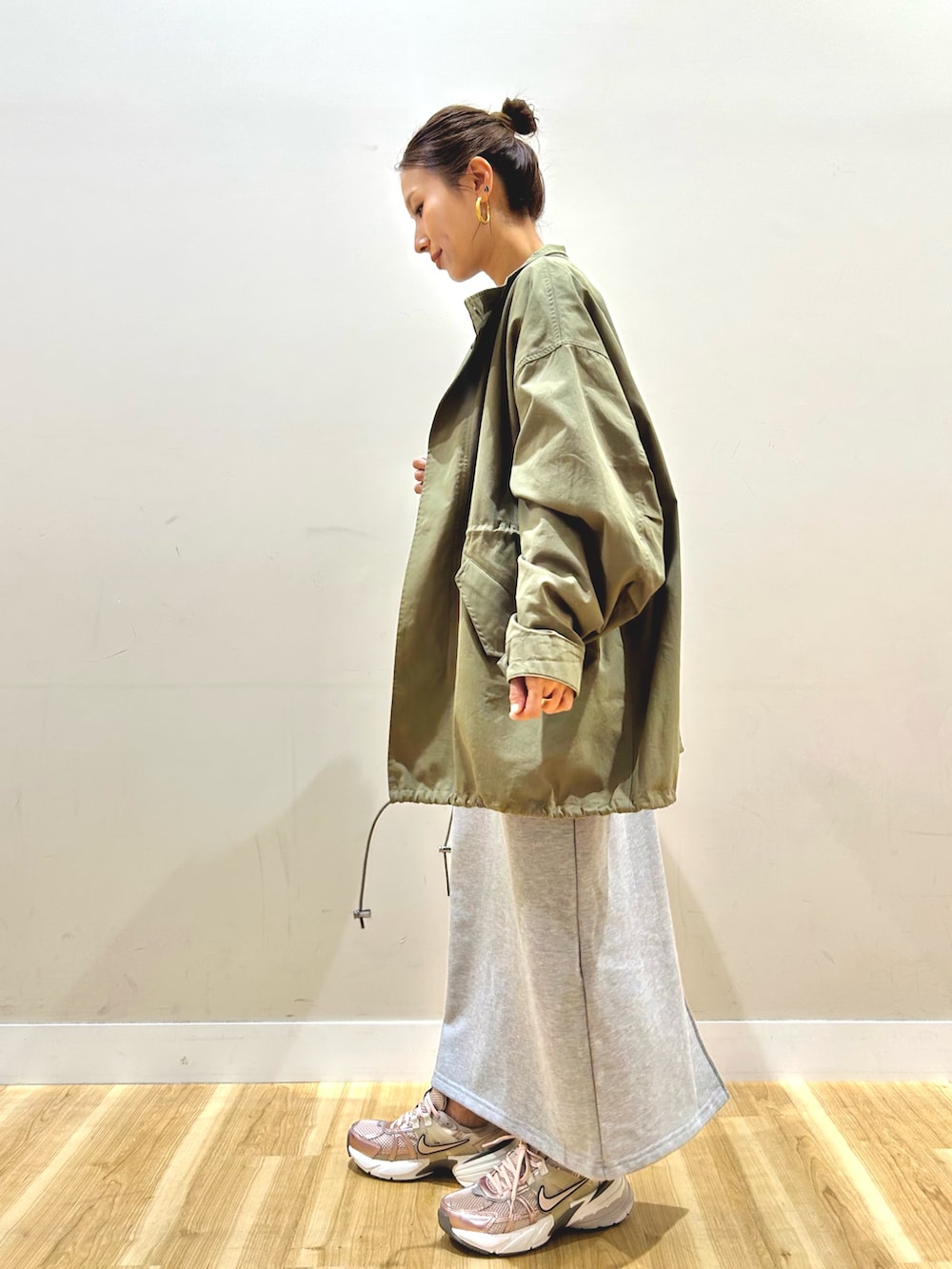 グリーン系のモッズコート、グレー系のワンピース、ブラウン系のショルダーバッグを着用したレディースの春コーディネートの2枚目の写真