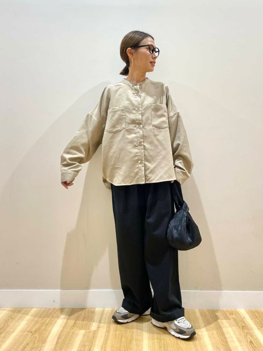 ブラック系のハンドバッグ、ベージュ系のTシャツ/カットソー、ブラック系のチノパンツを着用したレディースの秋コーディネートの2枚目の写真